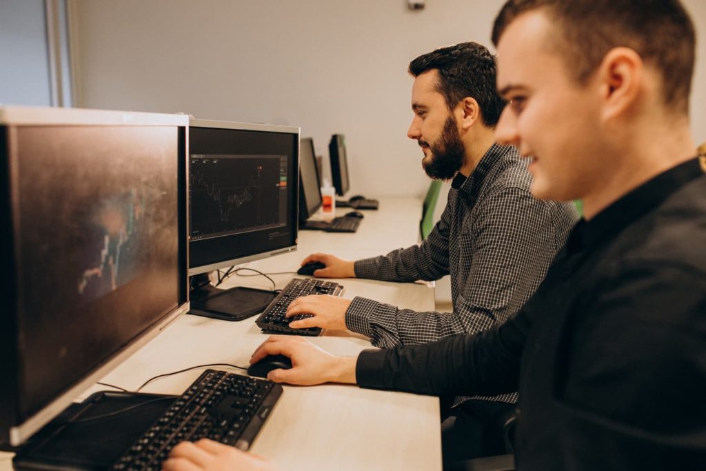 Dva muškarca rade na računalima u uredu agencije za digitalni marketing.